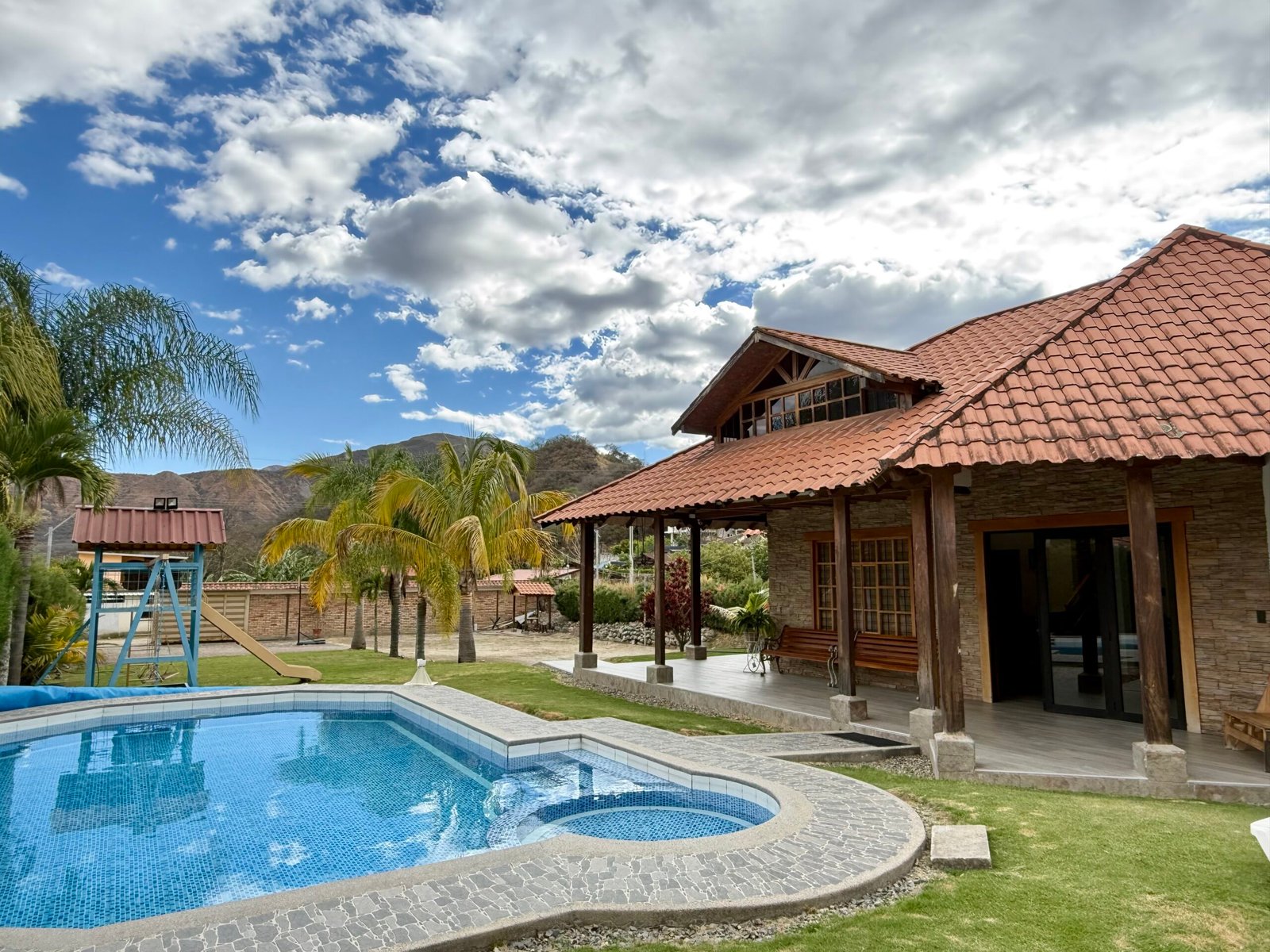 Exterior of the hacienda-style home with swimming pool and mountain backdrop