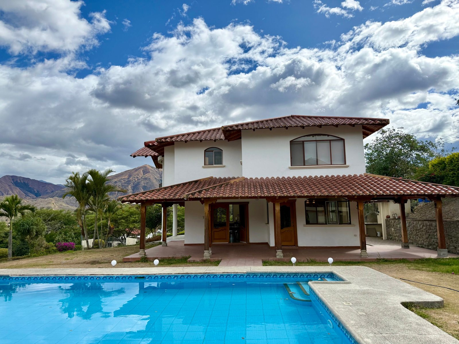 Two-story country home with pool and mountain backdrop