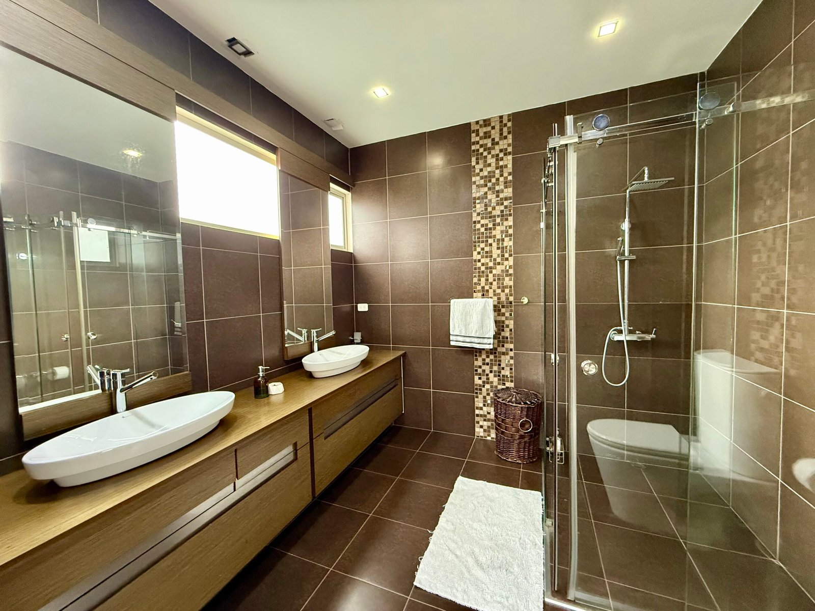 Modern bathroom with dark wood cabinetry and glass shower