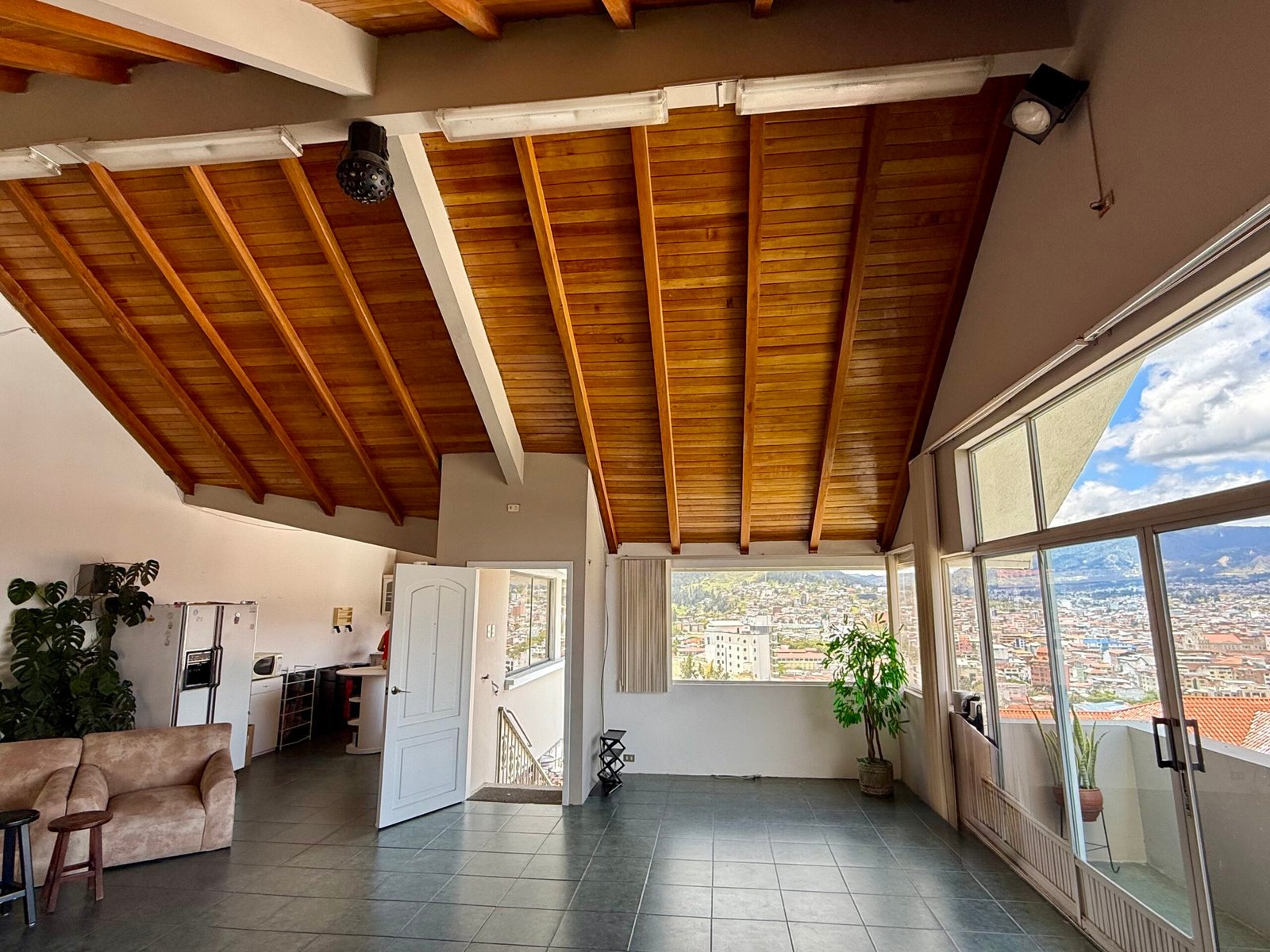 Spacious event hall with exposed wood beams and city views