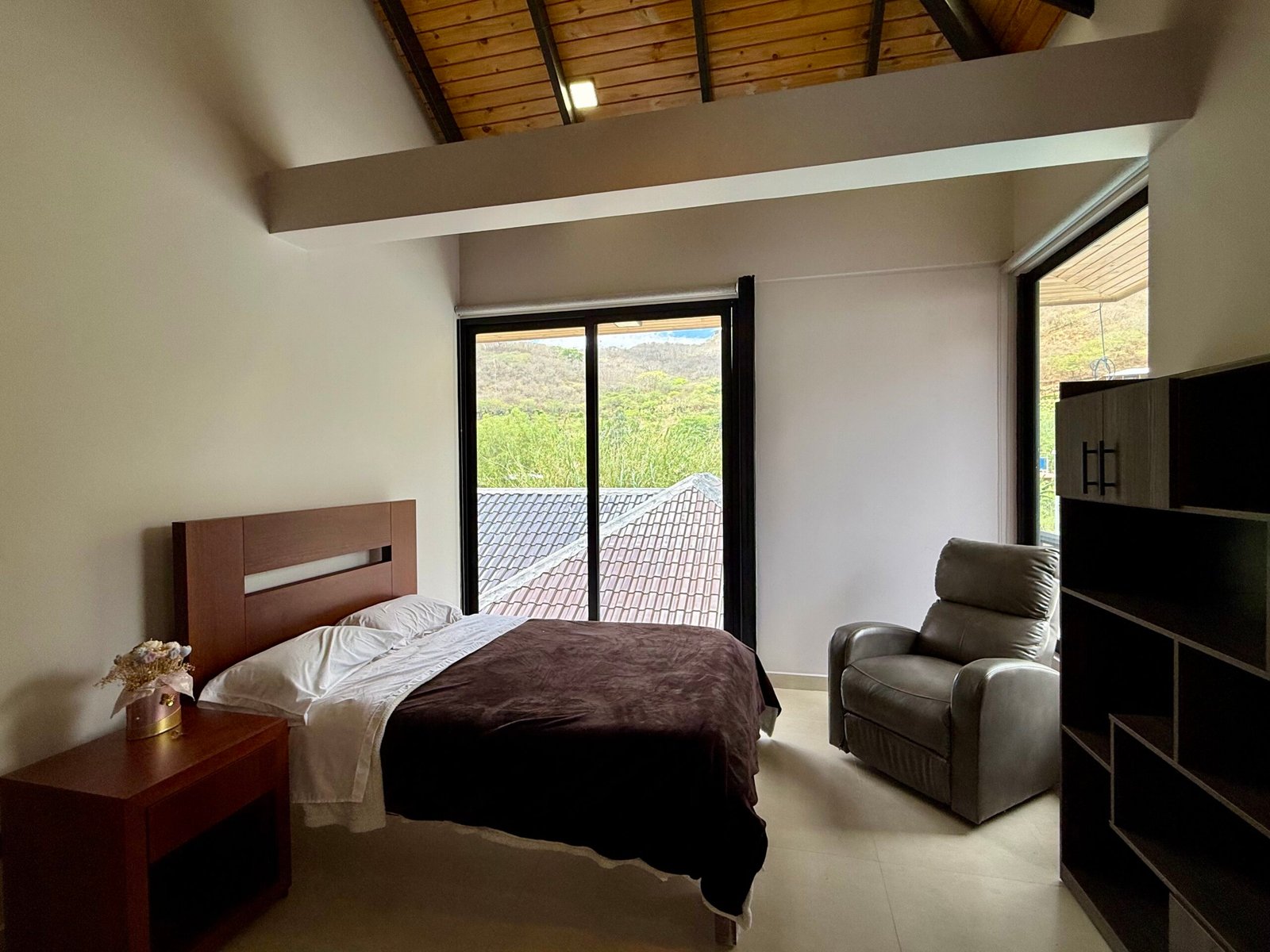 Bedroom with high wood ceiling and large windows